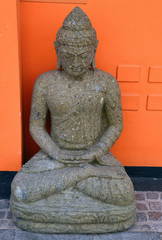 The Budha statue against orange wall.