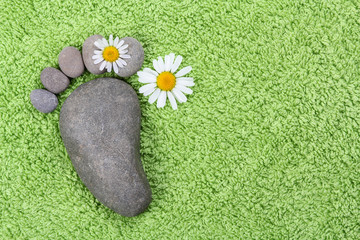 Fußabdruck aus Steinen mit Kamilleblüten
