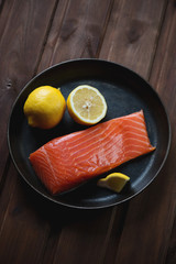 Frying pan with salted trout filet and lemon, high angle view