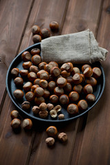 Frying pan with hazelnuts over wooden background, studio shot