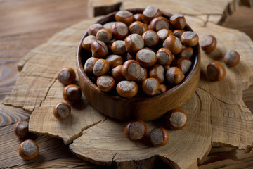 Bowl full of hazelnuts over wooden background, studio shot