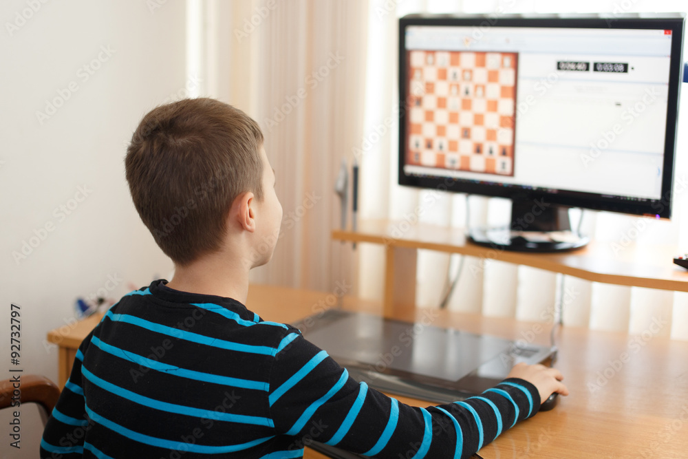 Wall mural little boy play online chess at home