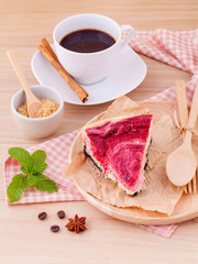 Homemade raspberry cake with cup of coffee on wooden background.