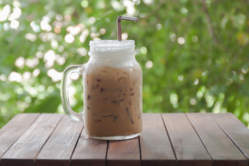 Ice coffee on a wooden table with nature background