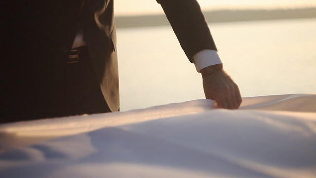 man covers tablecloth on the shore of the lake