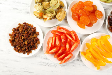 Different products on saucers on wooden table, top view