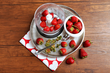 Ripe strawberries in blender on metal tray on wooden table, top view