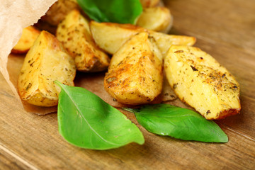 Baked potatoes in parchment on wooden table, closeup