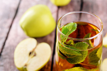 Glass of apple juice with fruits and fresh mint on table close up