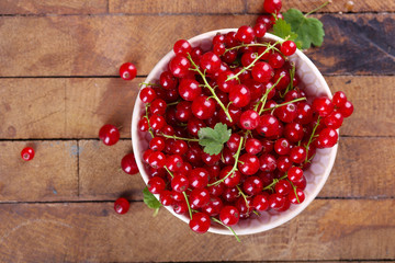 Fresh red currants in bowl on wooden table close up