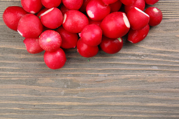 Heap of fresh radishes on wooden table close up background