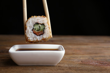 Dipping roll in sauce on dark background