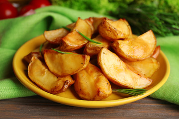 Baked potato wedges on wooden table, closeup
