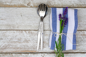 silver cutlery and a blue white napkin with lavender decoration and empty copy space in vintage country style
