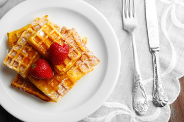 Sweet homemade waffles with strawberries  on plate, on table background