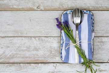 silver cutlery on blue white saucer plate,napkin with lavender decoration and empty copy space in...