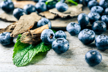 Tasty ripe blueberries with green leaves on wooden table close up
