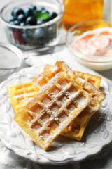Sweet homemade waffles on plate, on color wooden background