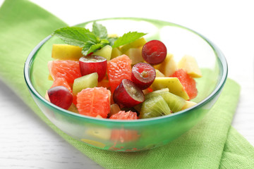 Fruit salad in glass bowl, on light wooden background