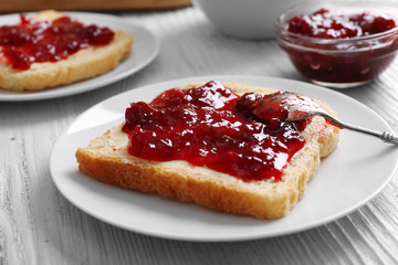 Bread with butter and homemade jam in white plate, closeup