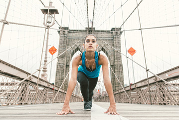 beautiful girl making stretching at early morning before running. brooklyn bridge and new york...