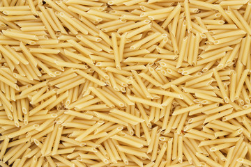 dry uncooked penne lisce pasta texture background