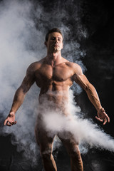 Totally naked male bodybuilder with smoke hiding genitalia