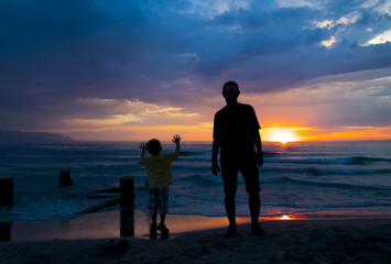 Father and son and a beautiful sunset over the sea