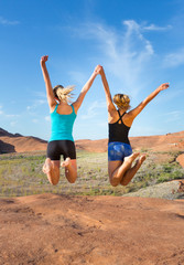 Two Girls Jumping for Joy in the Desert