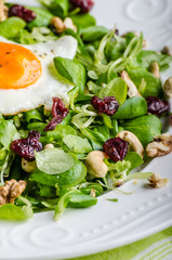 Fresh salad with nuts, raisins and fried egg