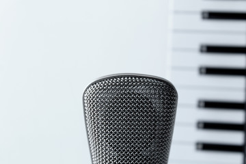 Microphone and blurred piano keys on background