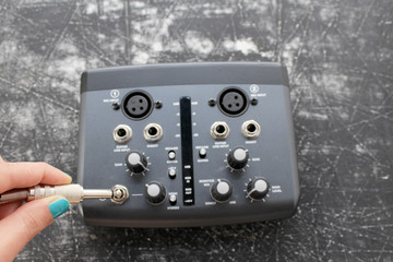 Audio interface for recording or mixing - sound/audio card, and woman's hand holding amplifier