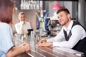 Attractive young barman is flirting with female customers