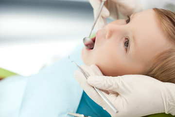 Skilled dental doctor is examining oral cavity of child