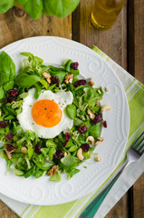 Fresh salad with nuts, raisins and fried egg