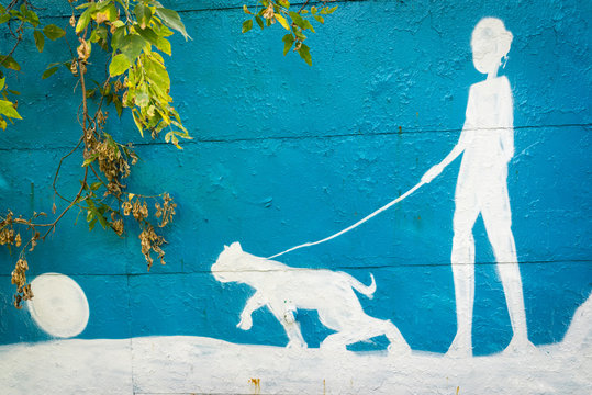 Moscow, Russia - September 27, 2015: a blue and white silhoette of a painted person on the garage wall. Man walking with a dog.
