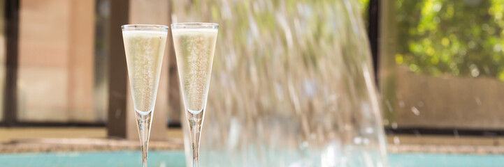 Two glasses of champagne near outdoor jacuzzi - obrazy, fototapety, plakaty