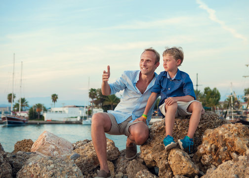 Father with son in tropical sea harbor on sunset time