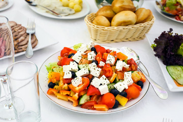 Salad vegetables and feta cheese, salad peppers, tomatoes and cheese, dish with salad, white tablecloth with a table, healthy food, diet food, Breakfast, lunch, and dinner. Healthy eating.