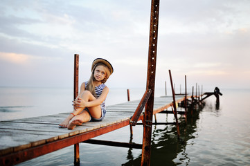 little girl in a striped t-shirt sitting on the bridge in the ba