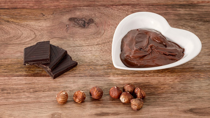 chocolate cream, hazelnut and chocolate on wooden table
