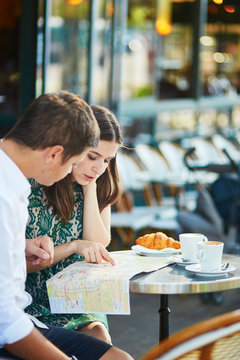 Young romantic couple with map in French cafe