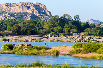 Picturesque tropical landscape in Hampi, India. Tungabhadra River in Hampi area with Anjaneya hill in the background which is believed to be the birthplace of Hindu God Hanuman.