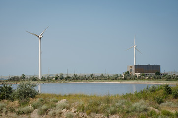 Fototapeta na wymiar a wind-powered generator at the base of the greenery and reservoir
