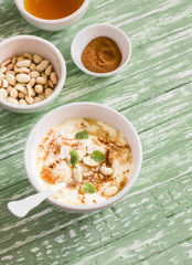 Greek yogurt with honey and nuts in a white bowl on  wooden surface, vintage and rustic style