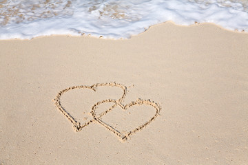 Two hearts drawn on the beach sand