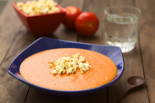 Ecuadorian tomato and potato cream soup served with popcorn on top (Selective Focus, Focus on the front of the popcorn on the soup)