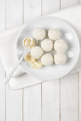 Coconut candies on white wood