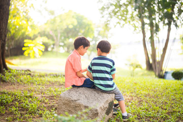 Fototapeta premium Little sibling boy sitting together in the park