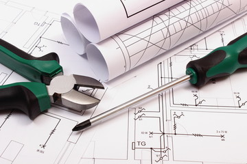 Rolls of diagrams and work tools on electrical construction drawing of house